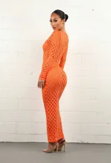 Vestido midi naranja de tejido calado con aberturas circulares, escote cuadrado y mangas largas ajustadas.