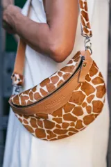 Riñonera color bronce con correa de cuero ajustable y cierre metálico.