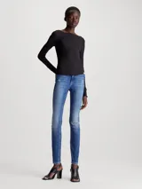 Jeans skinny de tiro alto color azul medio, con lavado gastado y roturas en las rodillas.