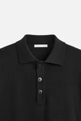 Polo de manga larga color negro, de punto tejido en hilatura de algodón, corte relaxed fit, con cuello solapa y cierre frontal de botonadura.