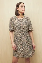 Vestido corto con estampado animal print en tonos beige, negro y marrón. Tiene corte holgado, mangas cortas y falda con vuelo.