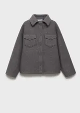Chaqueta color gris topo de tejido bouclé, con cuello camisero, cierre frontal con botones, dos bolsillos de parche con solapa y botón en el pecho, y mangas largas.