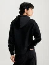 Buzo negro de corte relaxed, con capucha ajustable con cordón, puños y bajo acanalados. Presenta un logo de Calvin Klein Jeans estampado en el pecho.