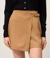 Short pollera de estilo sastre, color camel/marrón claro, con diseño de traspaso frontal asegurado por una hebilla.