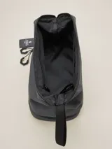 Neceser gris de poliéster con cierre superior y base con cierre adicional. Tiene una correa de mano y un colgante con el logo de la marca.