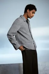 Sobrecamisa gris de tejido suave con cuello inglés, tapeta lisa, corte estándar, bolsillos superiores abiertos, abertura con botón en los puños, canesú en la espalda y bajo recto.