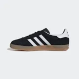 Championes Adidas Gazelle Indoor negros de gamuza con las tres tiras blancas y suela de goma color caramelo.