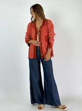Saco de punto color crudo con cuello camisero, cierre frontal con botones y bolsillos de parche.