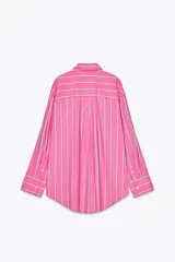 Camisa oversize rosada con rayas verticales blancas y celestes, cuello solapa, manga larga con puños abotonados, bolsillo de plastrón en el pecho y pinza en la espalda.