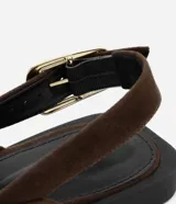 Zapatilla slingback marrón de material sintético con puntera fina, tira media con hebilla lateral dorada y tacón bajo.