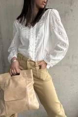 Camisa blanca de algodón con bordado inglés, cuello en V y mangas largas abullonadas.