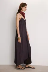 Vestido midi color morado oscuro, con escote en V y tirantes finos. El tejido presenta un acabado satinado y un efecto plisado o arrugado que le da fluidez.