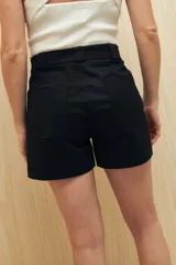 Short negro de gabardina, corte recto, con bolsillos delanteros y traseros, y presillas para cinturón.