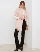 Bufandón tejido de poliéster, color rosa pálido con textura jaspeada en tonos pastel (naranja, lila, gris). Presenta un tejido grueso y flecos en los bordes.