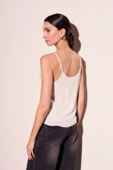Blusa lencera negra ajustada al cuerpo, sin mangas y con detalles delicados en el escote.