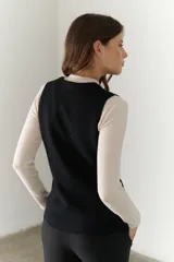 Chaleco gris de tejido de punto con cuello en V, cierre frontal con botones y bolsillos delanteros.