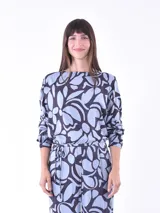 Blusa de mangas largas con estampado de hojas en tonos celeste y azul marino, con lazo en la cintura.