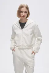 Campera blanca de jogging con felpa, corte cropped, cierre frontal con cremallera, capucha y bolsillo tipo canguro.