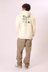 Sudadera con capucha de color verde oscuro (o verde petróleo) con efecto lavado, corte holgado y bolsillo canguro. Presenta un pequeño bordado blanco en el pecho con un diseño floral y texto.