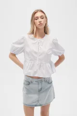 Blusa de algodón a rayas verticales color celeste y blanco, con cuello redondo, mangas cortas abullonadas y corte peplum.