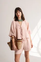 Blusa color crema confeccionada en lino, con mangas cortas, escote en V y lazos frontales.