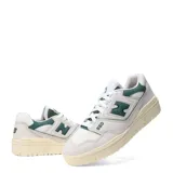 Championes New Balance modelo 550, color blanco hueso con detalles en verde oscuro. Presentan un diseño de corte bajo inspirado en el básquet, con paneles de cuero y malla, y el logo 'N' en verde oscuro. La suela es de goma color crema.