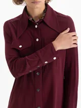 Camisa de mangas largas en viscosa color bordó, con calce relajado y bolsillos plaqué con tapa en el frente. El cuello, la cartera, los puños y el canesú están realizados en tela complemento. Los broches snap black níquel llevan el logo JCH grabado.