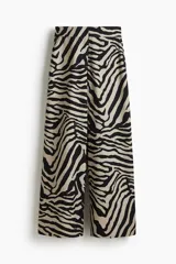 Pantalón amplio de sarga con estampado de cebra en tonos beige y negro, tiro alto, bolsillos al bies y cierre con botón y corchete ocultos.