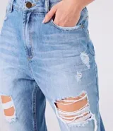 Pantalón de jeans celeste con corte mom, tiro alto, bolsillos delanteros y traseros, y roturas grandes en ambas rodillas.