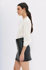 Minifalda negra de cuero sintético, corte recto, con bolsillos laterales y traseros.