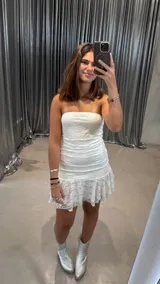 Vestido corto strapless blanco de encaje con volados en el ruedo.