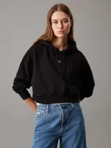 Buzo negro de felpa de algodón regenerativo, corte relaxed boxy, con capucha ajustable con cordón, puños y bajo de canalé e insignia con el monograma de Calvin Klein en el pecho.