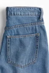 Pantalón de jean de tiro alto, corte amplio en las piernas y cinco bolsillos.