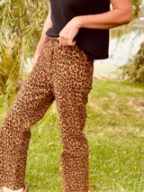 Pantalón de jean con estampado animal print en tonos beige y negro, de corte ancho y tiro medio. Presenta detalles de cuero bordó en la pretina y los bolsillos.