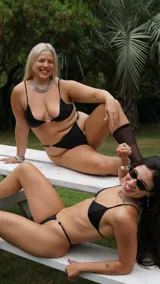 Sostén triangular negro con tirantes finos y detalle metálico plateado en el centro.