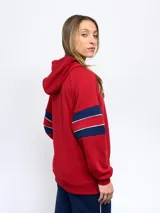 Campera de felpa con cierre frontal y capucha, color rojo, con detalles en azul marino y blanco en las mangas. Presenta el escudo del Club Nacional de Football en el pecho izquierdo y el logo de Umbro en el pecho derecho.