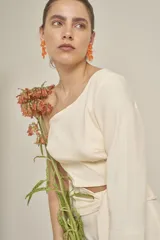 Top color crema de corte cropped, con un solo hombro y manga larga acampanada.