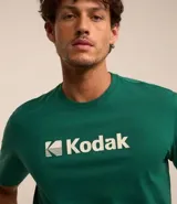 Remera blanca de algodón con cuello redondo y mangas cortas. Estampa frontal con el logo de Kodak en azul.