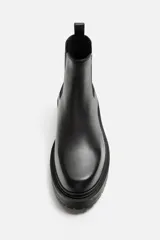 Bota Chelsea de cuero negro con elásticos laterales, tirador trasero y suela track.