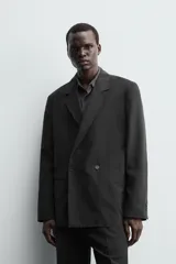 Blazer negra de corte relajado confeccionada en tejido con mezcla de lyocell. Tiene cuello con solapas de muesca, manga larga con puños abotonados, bolsillos de doble vivo en la cadera, bolsillo interior y cierre frontal cruzado con botones.