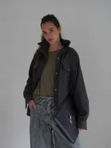 Camisa gris de lana con cuello clásico, cierre frontal con botones y dos bolsillos con solapa en el pecho.