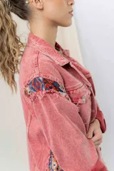 Campera de jean oversize, color rojo desgastado, con aplicaciones de tapicería multicolor de estilo étnico en hombros y ruedo, y terminaciones desflecadas.