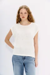 Remera blanca de lino con tachas termofijadas al tono en el delantero y moldería amplia.