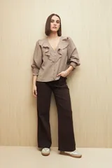 Camisa blanca a rayas verticales, con escote en V, mangas 3/4 con puños elastizados y volados.