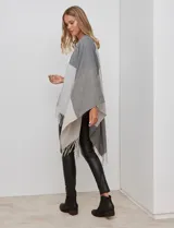 Ruana tejida con diseño colorblock en tonos borgoña, rosa viejo y beige. Presenta flecos en los bordes.