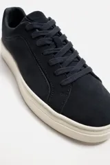 Zapatillas de hombre con cordones, fabricadas en piel serraje color azul marino. Suela plana color hueso y horma redonda.