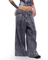 Pantalón de denim gris con lavado artesanal, corte sastrero de pierna ancha, tiro alto y pretina cruzada.