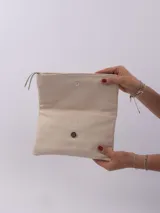 Sobre de mano color crema, con cierre de cremallera y tira de cuero para sujetar a la muñeca.