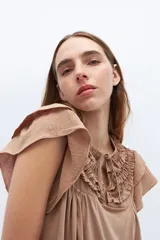 Blusa blanca de lyocell y algodón, con escote fruncido con volados y lazos.