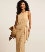 Vestido midi color beige, corte evasé, sin mangas, con lazo lateral y cierre trasero con cremallera.